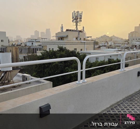 מעקה על גג עם נוף עירוני בשקיעה